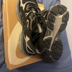  Asics skor  - Säljer ett par snygga och bekväma svarta och grå sneakers från Asics. Skorna har en robust sula och klassisk snörning, perfekt för både träning och vardag. De är i mycket bra skick och kommer i originalkartong.