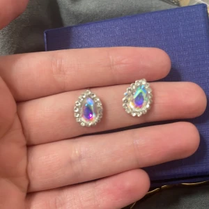 Glittriga örhängen med pärlor - Snygga örhängen med en droppformad design och glittrande stenar i mitten. De är omgivna av små pärlor som ger en elegant touch. Perfekta för att lysa upp vilken outfit som helst.