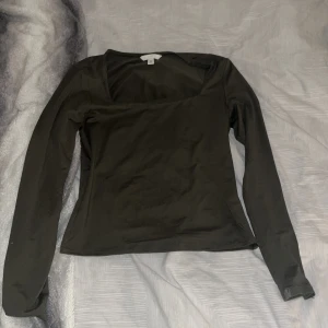 Svart långärmad topp från Hm - Snygg svart långärmad topp från Hm med en stilren design. Perfekt för både vardag och festliga tillfällen. Toppen har en fyrkantig halsringning som ger en modern touch.