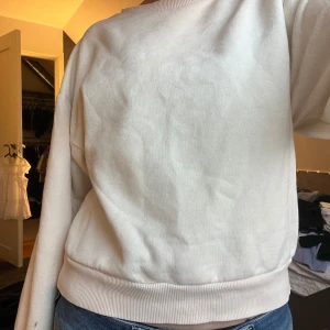 Vit sweatshirt från Gina Tricot - Säljer en vit sweatshirt från Gina Tricot, perfekt för en avslappnad stil. Tröjan har långa ärmar och ribbade muddar vid ärmslut och nederkant. Enkel och stilren design som passar till det mesta.