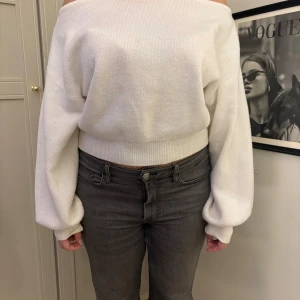 Vit offshoulder tröja - Säljer en stilren vit offshoulder tröja med långa ärmar. Tröjan har en ribbad kant vid midjan och ärmarna, vilket ger en snygg passform. 