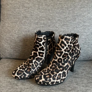 Leopardmönstrade stövletter med klack - Snygga leopardmönstrade stövletter med spetsig tå och klack. Perfekta för att ge din outfit en djärv touch. De har en stilren design och är lätta att matcha med olika stilar.