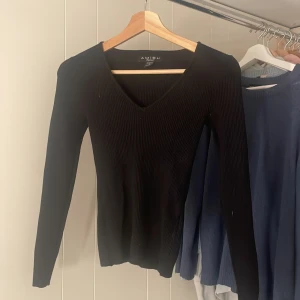 Svart ribbad tröja från Amisu - Säljer en stilren svart ribbad tröja från Amisu. Tröjan har en v-ringad design och långa ärmar, perfekt för en elegant look. Passar bra till både jeans och kjol. Perfekt för höst och vinter!jätte stretchig tröja🖤