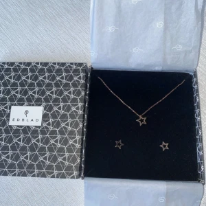 Stjärnformade smycken från Edblad - Elegant smyckesset från Edblad med ett halsband och matchande örhängen i stjärnform. Smyckena har en stilren design och kommer i en fin presentask. Perfekt för att ge bort eller unna sig själv.  Roseguldfärgade och aldrig använda!