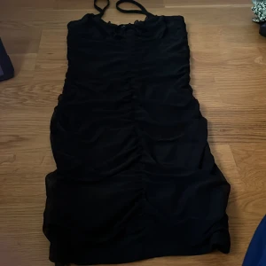 Svart klänning från H&M Divided - Säljer en snygg svart klänning från H&M Divided. Den är ärmlös med smala axelband och har en tight passform. Perfekt för festliga tillfällen!