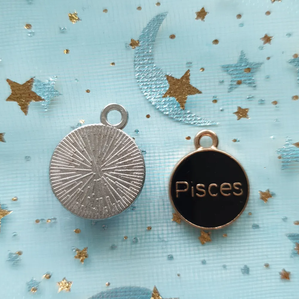 Säljer två superfina hängen med fiskarnas stjärntecken. Det ena hänget har en blå bakgrund med stjärntecknet och texten 'Pisces' i silver, medan det andra har en svart bakgrund med stjärntecknet i guld. Perfekta för att göra ett personligt halsband eller armband!. Asusteet.