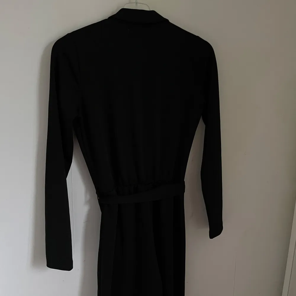Säljer en elegant svart långärmad byxsdress från Junkyard. Den har en stilren design med ett knytband i midjan för en snygg passform. Perfekt för både vardag och fest!. Mekot.