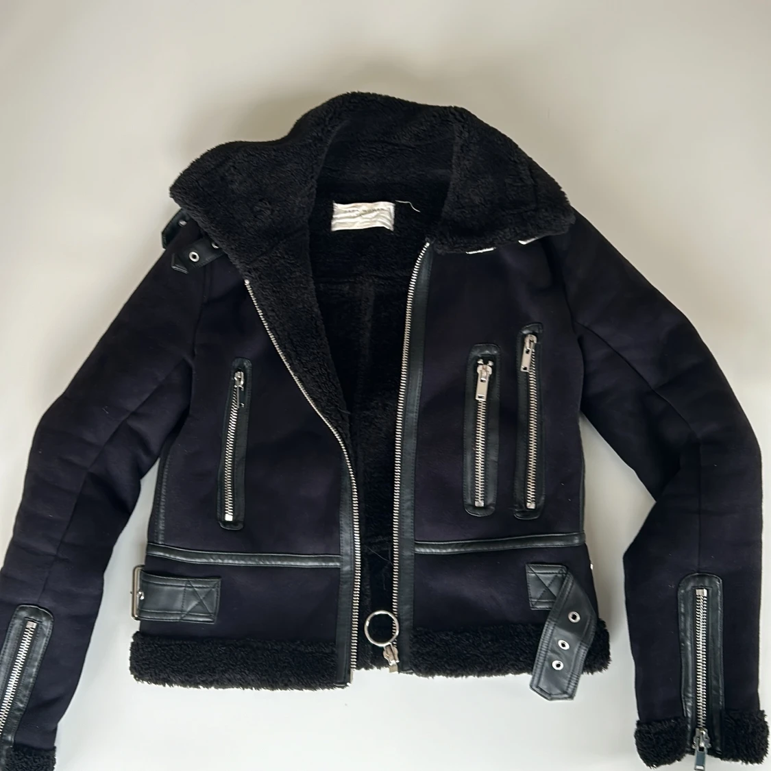 Svart jacka med dragkedjor och bälten