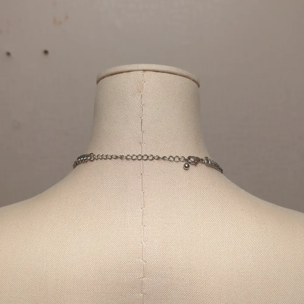 Säljer ett snyggt silverfärgat halsband med en stor glittrig detalj i mitten. Kedjan är robust och ger en cool look, perfekt för att piffa upp vilken outfit som helst. Detaljen i mitten är formad som en blomma med flera gnistrande stenar. Passar perfekt till fest eller en utekväll!. Accessoarer.