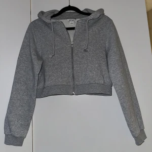 Monki croppad Hoodie - Oanvänd croppad zip up hoodie från Monki, sitter jätte fint på och stor o rymlig luva. 
