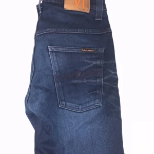 Mörkblå jeans från Nudie Jeans - Säljer ett par snygga mörkblå jeans från Nudie Jeans. De har en klassisk femficksdesign med en läderpatch baktill i midjan. Jeansen har en snygg tvätt och är perfekta för både vardag och fest.
