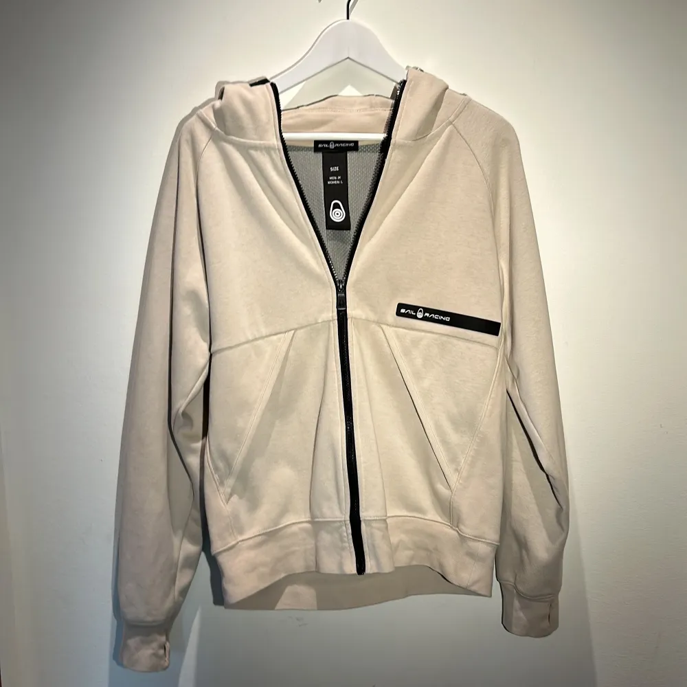 Säljer en stilren och bekväm beige hoodie från Sail racing. Storlek M. Perfekt för både höst och vår. Köpt i butik för 1000kr. Sparsamt använd, Inga defekter. Hoodies.