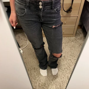 Grå/svarta jeans med hål - Säljer nu dessa snygga jeans från Gina som jag har klippt hål i!💘 använda fåtal gånger men är som nya de har absolut inga defekter förutom att de är lite slitna nere (sista bilden), storlekn på dessa byxor är 158!💘 skriv för frågor eller mer bilder!💘