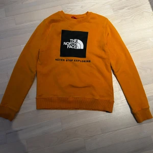  tröja från The North Face - Hej  Säljer en  tröja från The North Face som är i väldigt bra skick och endast använd några gånger.  med deras ikoniska logga och texten 'Never Stop Exploring' på framsidan. Tröjan har långa ärmar och ribbade muddar vid ärmslut och nederkant.     Jag köpare den för ca 900-1000kr. Det är storlek XL i ungdom och passar personer som är ca 150-160cm lång. Skriv om ni undrar något om tröjan.