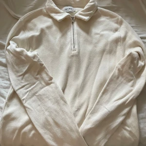 Beige tröja med dragkedja från East West - Säljer en stilren beige tröja från East West med dragkedja och krage. Perfekt för en avslappnad look. Tröjan har långa ärmar och är gjord i ett mjukt material.