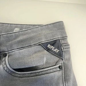 Grå jeans från Replay - Snygga grå jeans från Replay med klassisk femficksdesign. De har en stilren look med diskreta sömmar och en bekväm passform. Perfekta för en avslappnad stil.