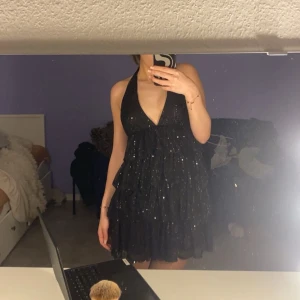 Svart glittrig klänning - Säljer min svarta volangklänning då den tyvärr inte kommer till användning 
