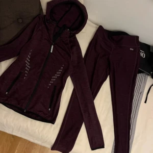 Vinröd träningsjacka med huva - Snygg vinröd träningsjacka med huva och dragkedja. Jackan har långa ärmar och diskreta mönsterdetaljer på framsidan. Perfekt för träning eller en aktiv vardag. Från Kappahl. Storlek S i båda. Skriv till mig privat om du vill köpa något separat!