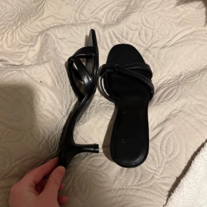 Svarta klackar  - Snygga svarta klackar med korsade remmar. Perfekta för en stilren look. Ca 5cm klack 