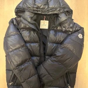 Svart Moncler giubbotto - Säljer en stilren svart pufferjacka från Moncler. Priset är på grund av att de är en bytt dragkedja, för den andra strulade. Storlek 2 passar s och m. Kvitto finns !!!