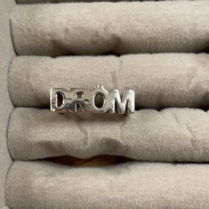 Silverfärgad ring med texten 'DRÖM' - Ring från l8hasselblad med motivet DRÖM🥰 bra skick så använd ett fåtal gånger🙌