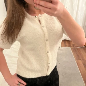 Vit kofta med pärlknappar - Säljer en söt vit kofta med korta ärmar och pärlknappar. Super gosig och sticks ej, nyskick med prislappen kvar, superfin till vardags och är även snygg med linne/tröja under, hör av er om mer frågor💕💕nypris: 399kr, passar dessutom allt från Xs-M