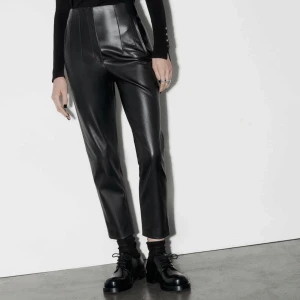 Svarta skinnbyxor - Snygga svarta skinnbyxor med hög midja och en stilren, rak passform. Perfekta för en trendig look med en modern twist. Byxorna har en slät yta och är enkla att matcha med olika toppar och skor.
