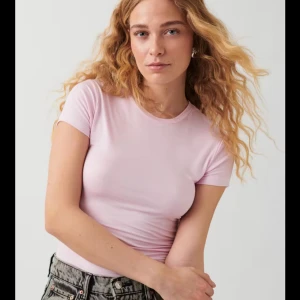 Ljusrosa t-shirt - Snygg ljusrosa t-shirt med korta ärmar. Perfekt för en avslappnad stil och enkel att matcha med olika outfits.