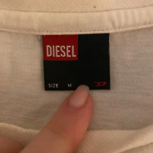 Vit långärmad tröja från Diesel - Säljer en stilren vit långärmad tröja från Diesel. Tröjan har en rund halsringning och en diskret logga på framsidan. Det är storlek M men skulle säga att det är mer än S och passar också på xs fast med en avslappnade look💕 Den är i toppen skick bara ett litet mini hål precis bredvid loggan (se blid)