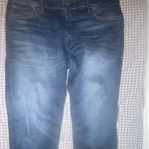 Blå jeans från Jack & Jones - Säljer ett par snygga blå jeans från Jack & Jones i modellen Slim Straight Tim. De har en klassisk design med orangea detaljer och en bekväm passform.