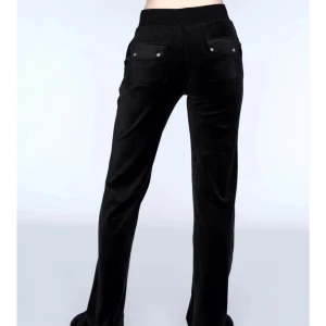Svarta byxor i sammet - Snygga svarta byxor i mjukt sammetstyg med hög midja och raka ben. Byxorna har fickor bak med knappdetaljer. Perfekta för en stilren look.