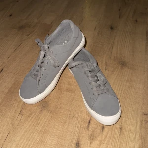 Grå sneakers med snörning - Snygga grå sneakers med snörning och en vit sula