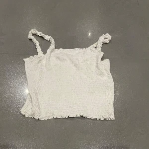 Vit linnetopp från new Yorker - Säljer en söt vit linnetopp från new Yorker i storlek XS. Toppen har smala axelband och en smockad design som ger en fin textur. Skriv privat för fler bilder eller frågor :) 