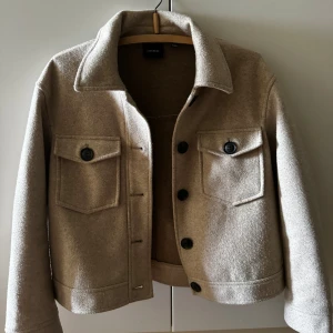 Höstjacka - Beige höstjacka med svarta knallar från vero Moda, modellen är lite kortare och tyget har lite struktur.   Väldigt snygg och mysig jacka/ kappa.   Passar dem som har storlek  M/L