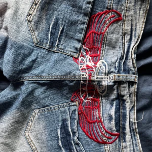Capris med broderi på baken - Lågmidjade capris/trekvartsbyxor med broderi på rumpan i rött och vit. Destressed wash.