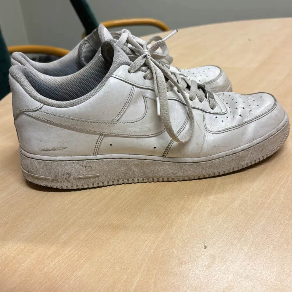 Säljer ett par vita Nike Air Force sneakers. De är välanvända med en del slitage, speciellt på sulorna och insidan. Skorna har klassisk snörning och är i skinnmaterial. Perfekta för en casual look!. Skor.