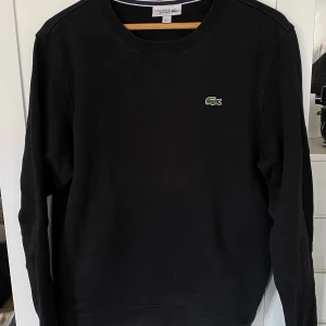 Svart tröja från Lacoste - Säljer en stilren svart tröja och ett par matchande byxor från Lacoste. Tröjan: 200kr Byxorna: 250kr. Båda för 375kr