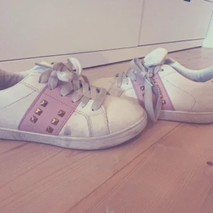 Vita sneakers med rosa detaljer och nitar - Säljer ett par vita sneakers med rosa detaljer och coola nitar. Skorna har snörning och är perfekta för en avslappnad stil. De är lite använda men fortfarande i bra skick. Perfekta för vår och sommar!🎀🎀🎀storlek 37/38