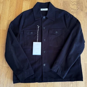 our legacy evening coach jacket - En svart Our legacy brushed cotton overshirt helt oanvänd, endast testad i butik, köpt på Meadow i Malmö för 1700 kr, kvitto finns, storlek 48