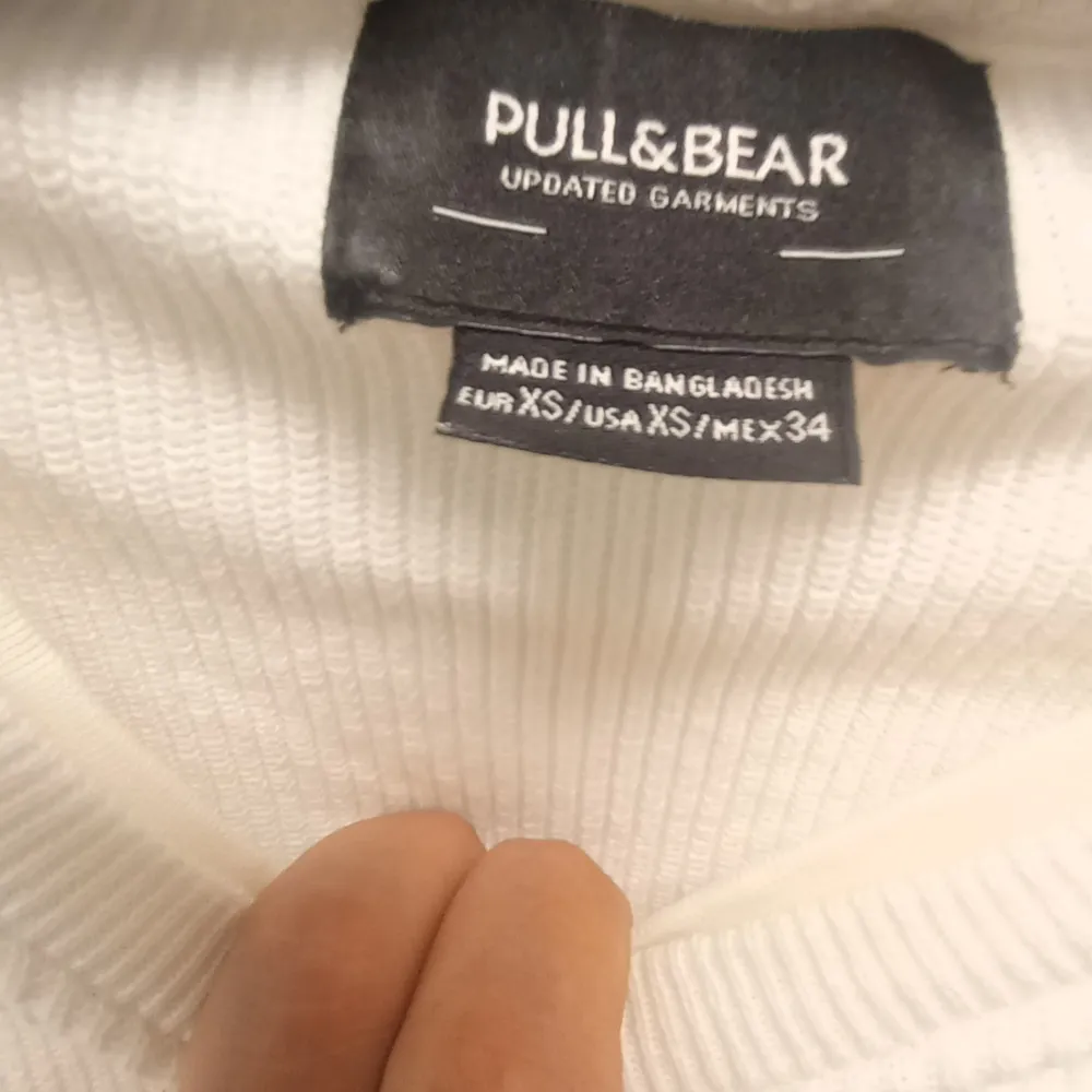 Säljer en stilren vit tröja från Pull&Bear i storlek XS. Tröjan är långärmad och har en enkel design med en liten slits vid nederkanten. Perfekt för en avslappnad look eller att ha som basplagg i garderoben. Den är i bra skick och redo för en ny ägare!. Tröjor & Koftor.