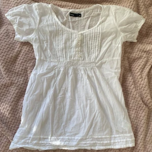Vit blus från Cubus - Säljer en söt vit blus från Cubus i storlek 36. Den har korta ärmar och knappar framtill. Perfekt för sommardagar eller en avslappnad vårlook. Blusen är i ett lätt och luftigt material, vilket gör den bekväm att bära.