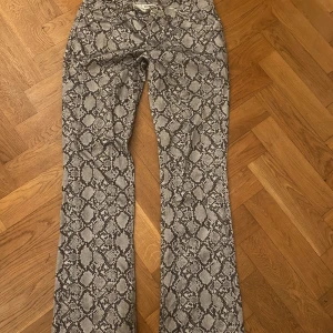 Orm skinn byxor  - Low waist flared ormskinns-byxor från weekday 