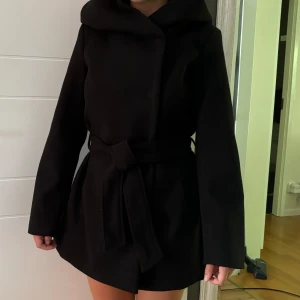 Kappa med luva!  - Pris är reducerbart🩷I princip ny! Köpt för 600 på New Yorker förra året. Den har stor luva. Materialet är mocka typ och den är väldigt tjock. Har tre vals knäppning då de finns två rader av knappar hårdare och lösare. Samt midjebandet då. 