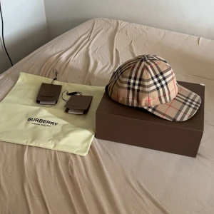 Burberry keps - Hej, jag säljer min burrbery keps i storlek L för 1000kr, priset kan ändras. Box följer med, det ända är att en knapp där bak är sönder som ni ser på sista bilden, det påverkar inget och går att fixa i ett skomakeri för mindre än 100kr.