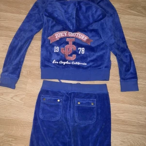 Blå velour hoodie från Juicy Couture - Säljer en supermjuk och snygg blå velour hoodie från Juicy Couture. Den har en dragkedja framtill och fickor baktill. På baksidan finns ett glittrigt Juicy Couture-tryck i rosa. Perfekt för en cool och charmig look! 💙