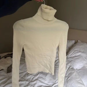 Vit polotröja i ribbad bomull - Säljer en stilren vit polotröja i ribbad bomull. Perfekt för kyliga dagar med sin höga krage och långa ärmar. Tröjan är i mycket bra skick och passar både till vardags och lite finare tillfällen. Supermjuk och bekväm! Använd en gång 🤍