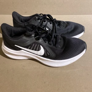 Svarta Nike Runner löparskor - Säljer ett par svarta Nike löparskor i bra skick. De har en vit sula och klassisk Nike-logga på sidan. Perfekta för träning och vardagsbruk. Skorna har snörning för en säker passform.