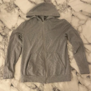 Grå hoodie med dragkedja - Grå huvtröja! Perfekt för både höst och vår, och funkar lika bra till vardags som till träning. Den är gjord i mjukt material och har fickor framtill för extra bekvämlighet! 🩶DM vid frågor osv!
