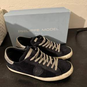 Säljer ett par Philippe Model sneakers i svart mocka med grå snörning. Skorna har en klassisk design med en vit sula och är i bra skick. Perfekta för både vardag och festliga tillfällen.