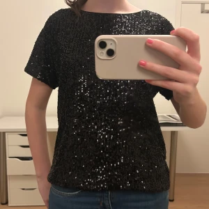 Svart glittrig topp - Snygg svart glittrig topp perfekt för festliga tillfällen. Den har korta ärmar och en bekväm passform. Perfekt att matcha med jeans eller kjol för en kväll ute. ✨